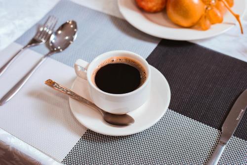 a cup of coffee on a plate with a spoon at Reikartz Kokand in Kokand