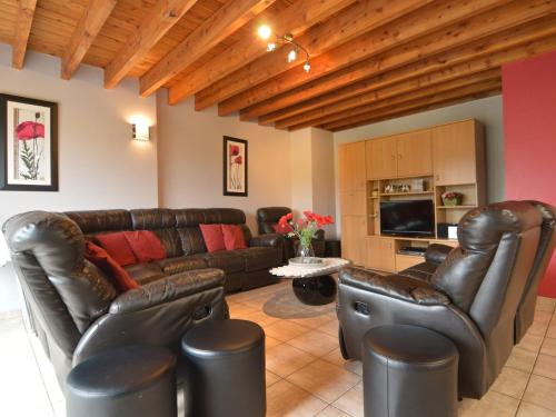 ein Wohnzimmer mit einem Ledersofa und Stühlen in der Unterkunft Modern Cottage in Baugnez Malmedy with Sauna in Arimont