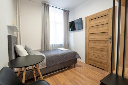 Schlafzimmer mit einem Bett, einem Tisch und einem Fenster in der Unterkunft Apartamenty Słowackiego 16 in Posen