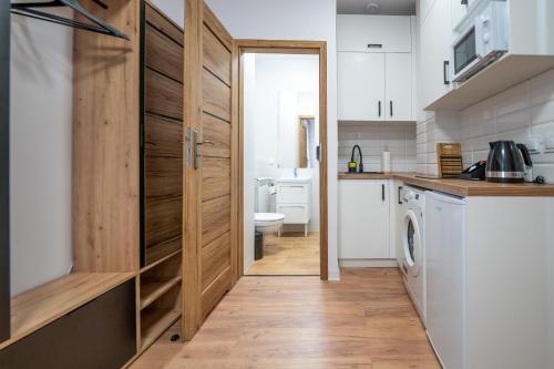 a kitchen with a wooden door and a washer and dryer at Apartamenty Słowackiego 16 in Poznań