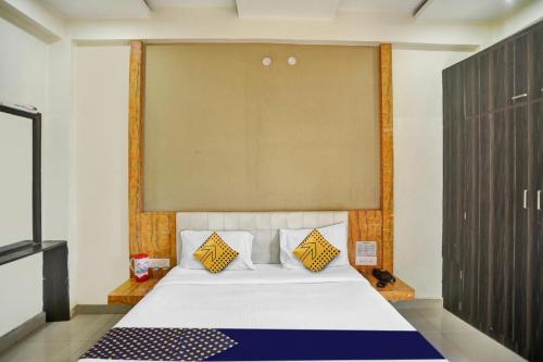Un dormitorio con una cama blanca con almohadas amarillas y azules en Hotel Kamdhenu inn Prayagraj, en Lukerganj