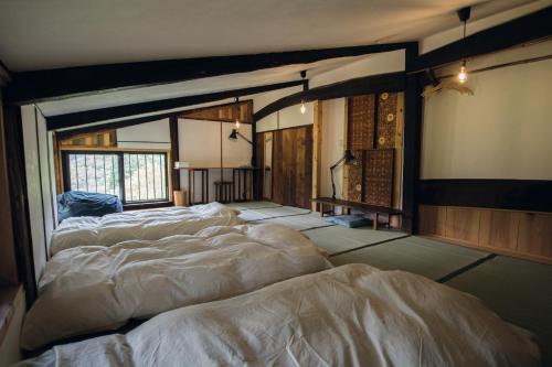 una habitación con 4 camas alineadas en una habitación en Hostel Yui-an en Nagiso