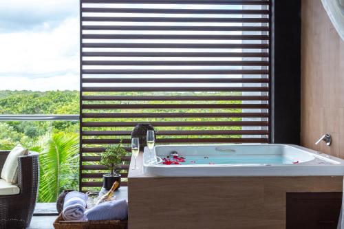 ein Bad mit einer Badewanne vor einem Fenster in der Unterkunft Fabulous & Exclusive Apartments With Sea View Pool BBQ Garden in Akumal