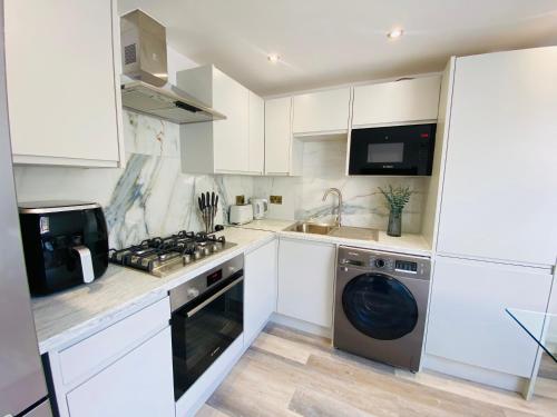 a kitchen with white cabinets and a washer and dryer at Apartment in Stepney Green in London