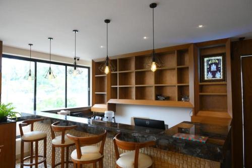 a kitchen with a bar with wooden stools at SHRREYAS INN in Kundapur
