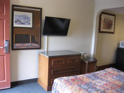 Habitación de hotel con cama, vestidor y TV. en Sunshine Motel, en San Bernardino
