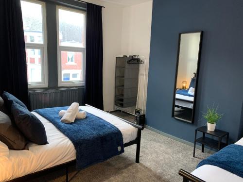 a bedroom with blue walls and a bed with a mirror at Saltwell St - Delightful 3 Bedroom free parking free wifi in Gateshead