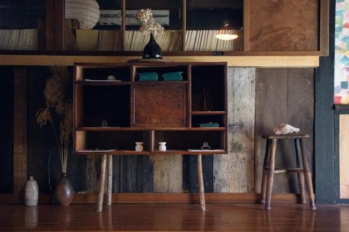 ein Holzregal in einem Zimmer mit zwei Hockern in der Unterkunft Hostel Yui-an in Nagiso