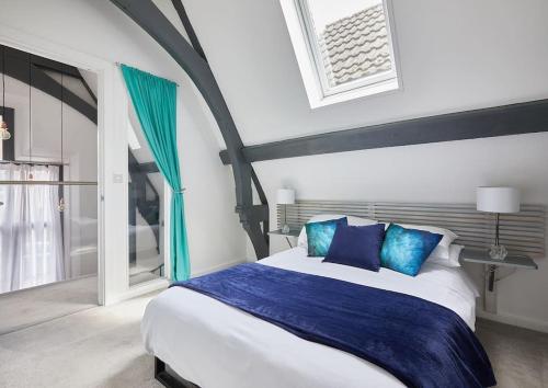 ein Schlafzimmer mit einem großen Bett mit blauen Kissen in der Unterkunft The Chapel Cottage by Ritual Stays in Hemel Hempstead
