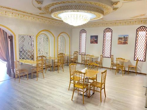 jadalnia ze stołami i krzesłami oraz żyrandolem w obiekcie HOTEL UZBEGIM w Urgenczu
