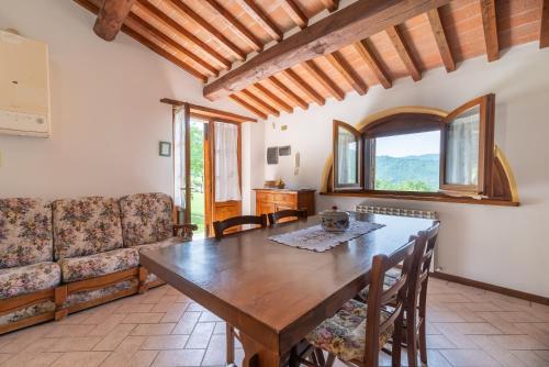 a dining room with a wooden table and a couch at Villa in esclusiva - Pugnano Alto in Lisciano Niccone