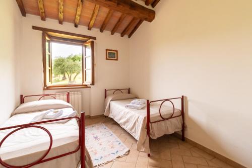 a bedroom with two beds and a window at Villa in esclusiva - Pugnano Alto in Lisciano Niccone