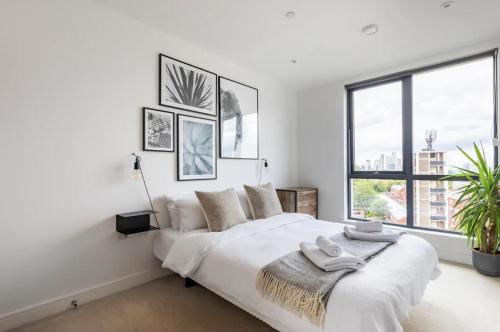 a white bedroom with a large bed and windows at Modern 1 bed l City views l Work Space in London