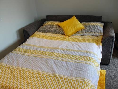 a bed with a yellow pillow on top of it at The Bubble Hideaway - A Little Oasis near the Sea in Whitstable