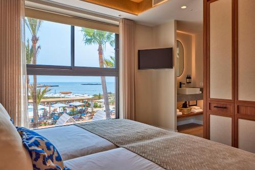 a bedroom with a bed and a view of the beach at Universal Grand León & Spa in Colònia de Sant Jordi