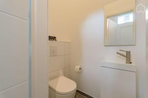 ein weißes Bad mit einem WC und einem Spiegel in der Unterkunft Modernes Apartment in Berlin in Berlin
