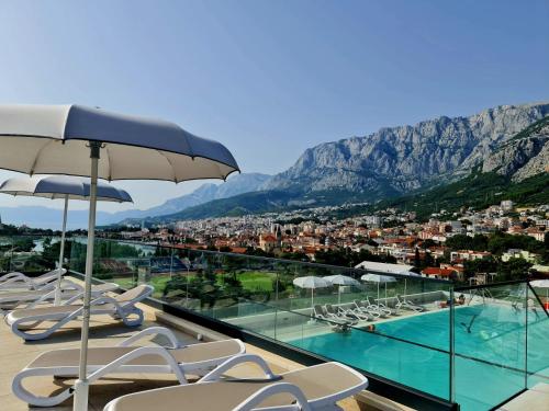 a swimming pool with chairs and an umbrella at Apartman Nika Makarska in Makarska