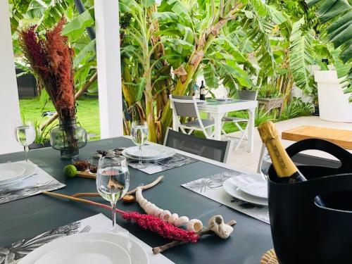 a table with a wine bottle and glasses on it at Villa à 100 m à pied de la plage in Sainte-Anne