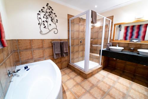 a bathroom with a tub and a shower and a sink at Gooderson Drakensberg Gardens Golf & Spa Resort in Drakensberg Garden