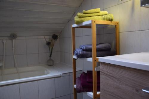 y baño con estante con toallas y bañera. en Am Bergangerl, en Ettal