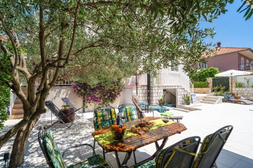 patio ze stołem i krzesłami pod drzewem w obiekcie Apartments Villa Key w mieście Cavtat