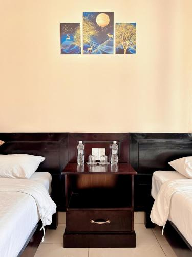 a bedroom with two beds and a wooden nightstand at Tuần Châu - Phương Đông Motel Hạ Long in Ha Long