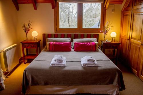 Un dormitorio con una cama grande con toallas. en SIETEFLORES Lodge, en San Martín de los Andes