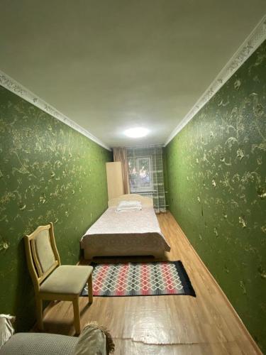 um quarto com uma parede verde com uma cama e uma cadeira em 3 комнатная квартира Аэропорт em Turksib