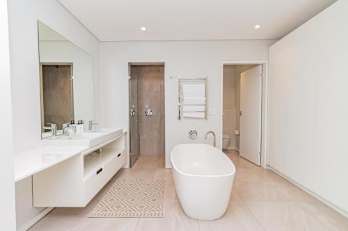 a white bathroom with a tub and a sink at Scholtz Penthouse in Cape Town