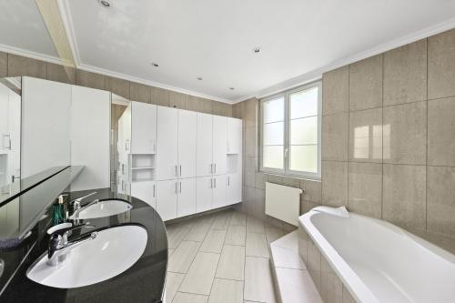 een badkamer met 2 wastafels en een bad bij Centrally located House with garden in Zürich