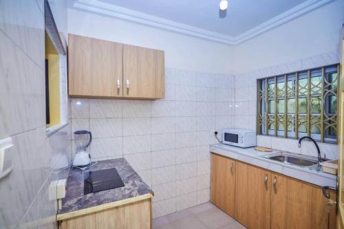 cocina con armarios de madera, fregadero y ventana en BH Apartment, en Kasoa
