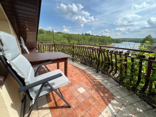 a porch with a wooden table and a chair and a river at Apartament na Kaszubach in Brodnica Dolna