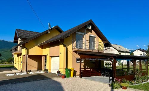a large yellow house with a porch and a balcony at Sweet Dreams Home in Korenica