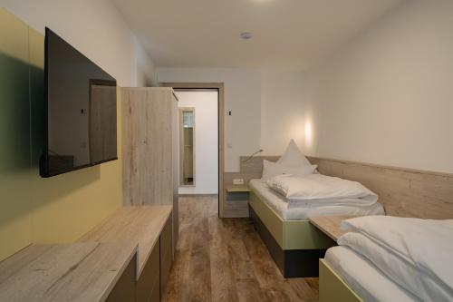 a room with two beds and a tv on the wall at Südseequartier in Elsterheide