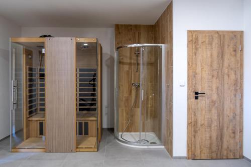 two wooden cabinets and a glass shower in a room at Penzion Tonička in Bulhary