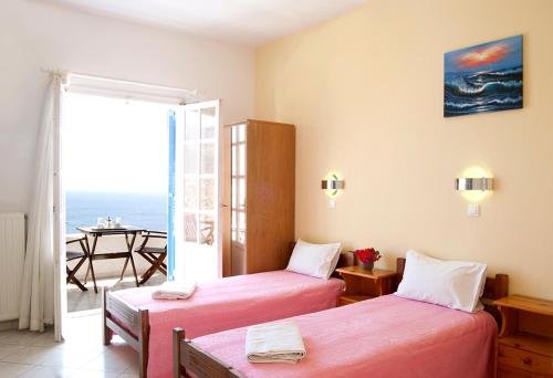 two beds in a room with a view of the ocean at Ios Pelagos in Ios Chora