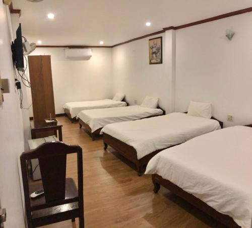 drie bedden in een kamer met witte lakens bij Mina Hotel in Vientiane