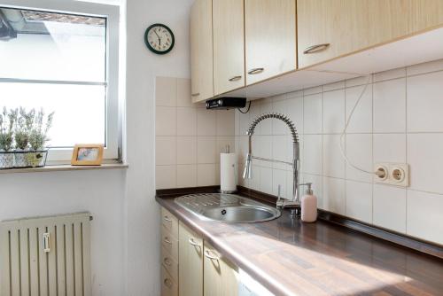 eine Küche mit einem Waschbecken und einer Uhr an der Wand in der Unterkunft Maisonette-bodenseetraum Amanda in Überlingen