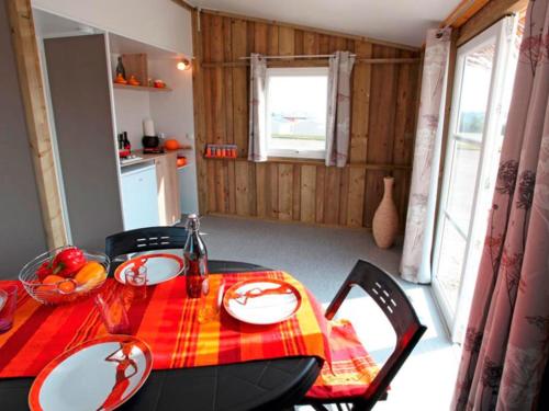a kitchen with a table with a red and yellow table cloth at Camping Ayguebère in Laruns