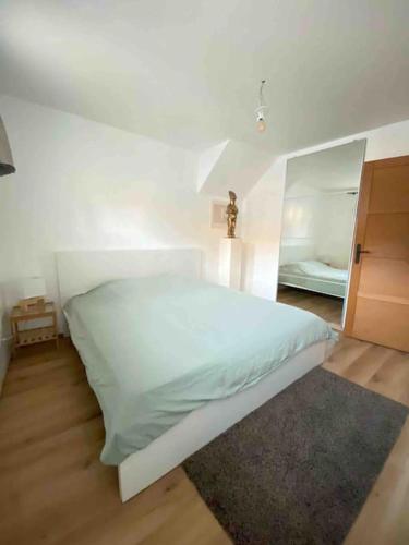 une chambre avec un lit blanc et un miroir dans l'établissement Joli logement de campagne, à Contamine-sur-Arve