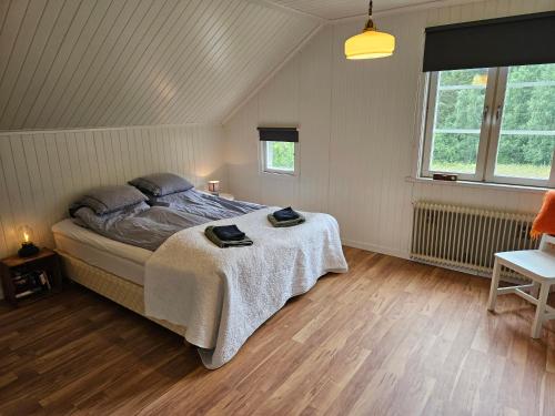 a bedroom with a large bed in a room with wooden floors at Mysigt hus med utsikt över fjäll och älv. in Järpen