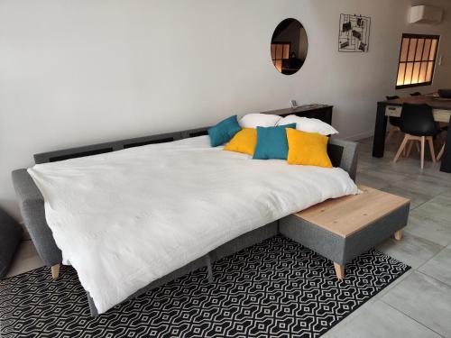 La Borie - Loft élégant et spacieux - WIFI في Puygouzon-et-Montsalvy: غرفة نوم مع سرير أبيض كبير مع وسائد ملونة