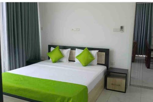 a bedroom with a large bed with green pillows at Next to Indian Ocean in Colombo