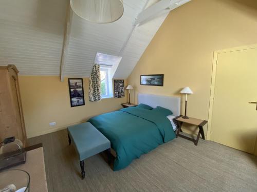 - une chambre avec un lit bleu et une chaise dans l'établissement Villa Kergariou, à Clohars-Carnoët