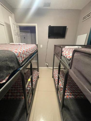a room with two bunk beds and a flat screen tv at Miami Vibes "Hostel-Like" Shared Room in North Miami