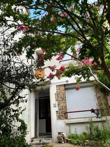 a white house with pink flowers in front of it at Grand logement Centre Ville Massy in Massy