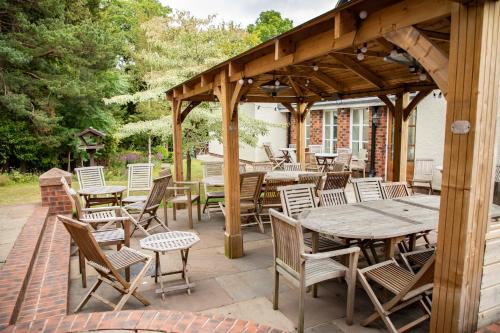 a wooden pavilion with tables and chairs on a patio at Mere Brook House in Wirral