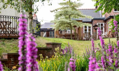 a garden with purple flowers in front of a house at Mere Brook House in Wirral