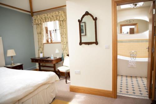 a bedroom with a bed and a bathroom with a tub at Mere Brook House in Wirral