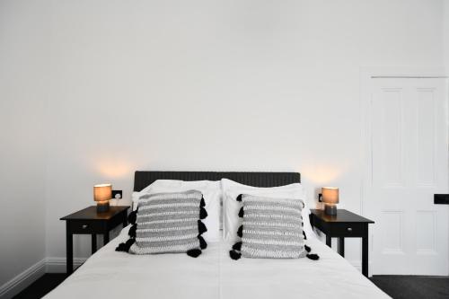 uma cama com almofadas brancas e duas mesas com candeeiros em Prestwick Green Pad em Prestwick